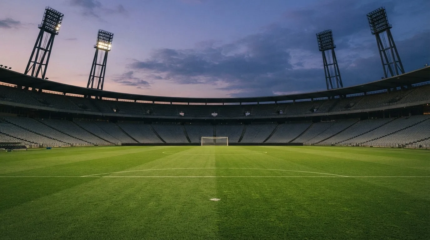 An empty football stadium with floodlight masts at dusk