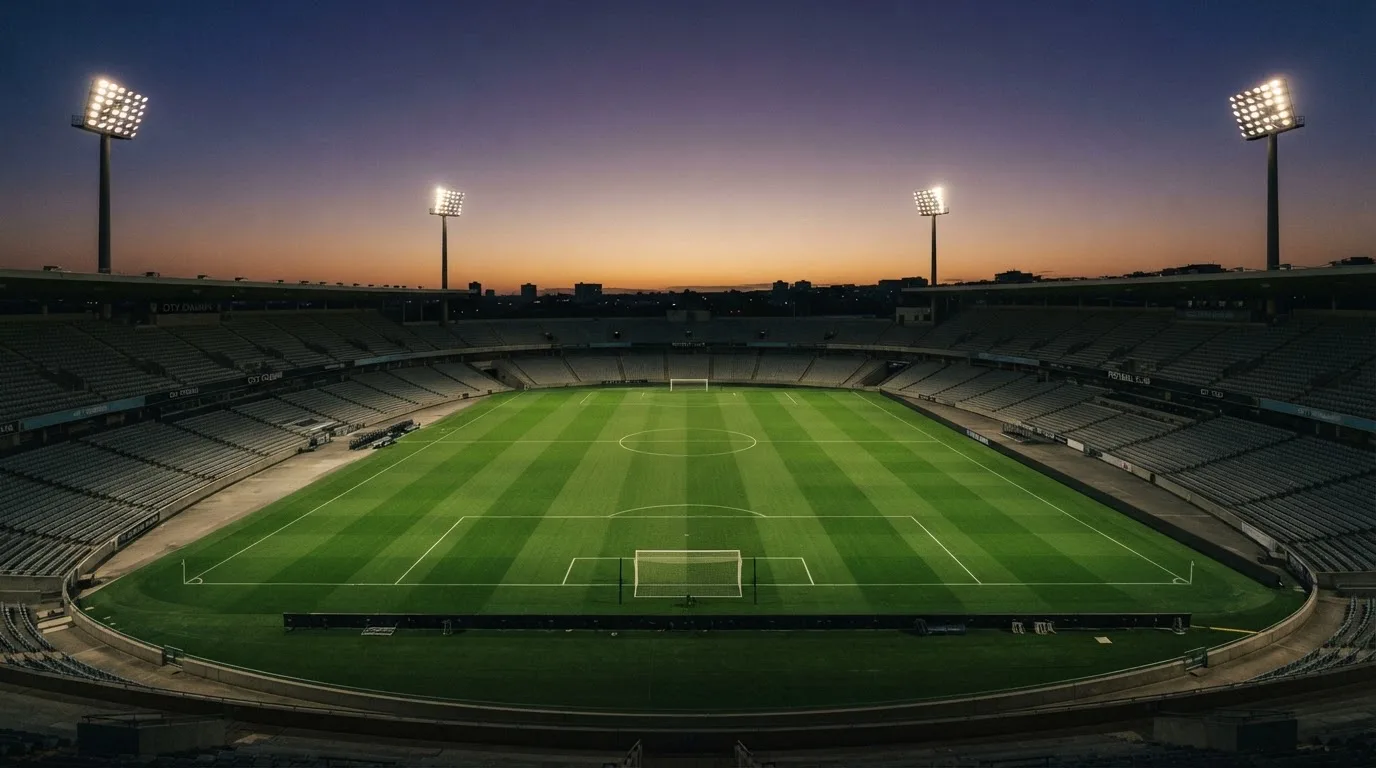 An empty football stadium with floodlight masts at dusk