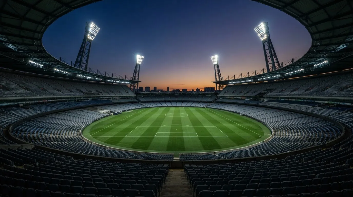 An empty football stadium with floodlight masts at dusk