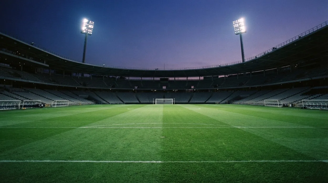 An empty football stadium with floodlight masts at dusk