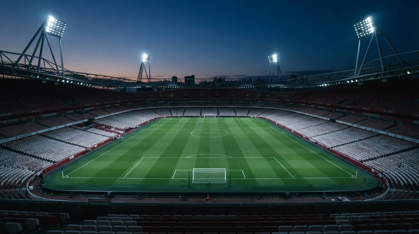 An empty football stadium with floodlight masts at dusk